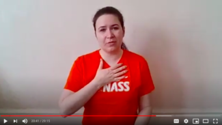 Zoë Clark sat wearing a NASS t-shirt and showing a breathing exercise with one hand on the top of her ribs
