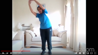 Screenshot of Susi standing, reaching her arms up and bending her spine to the side