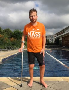 Darren Fletcher lives with axial SpA. He is wearing a NASS t-shirt and standing by the pool