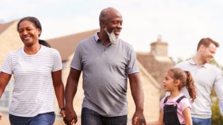 Smiling Multi-Generation Mixed Race Family Walking In Garden At Home