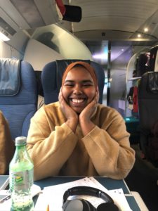 Safia Awil, smiling and sitting on a train
