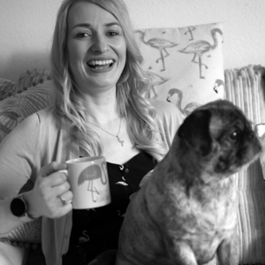 Black and White image of Jen parker holding a cup of tea with her dog on her lap
