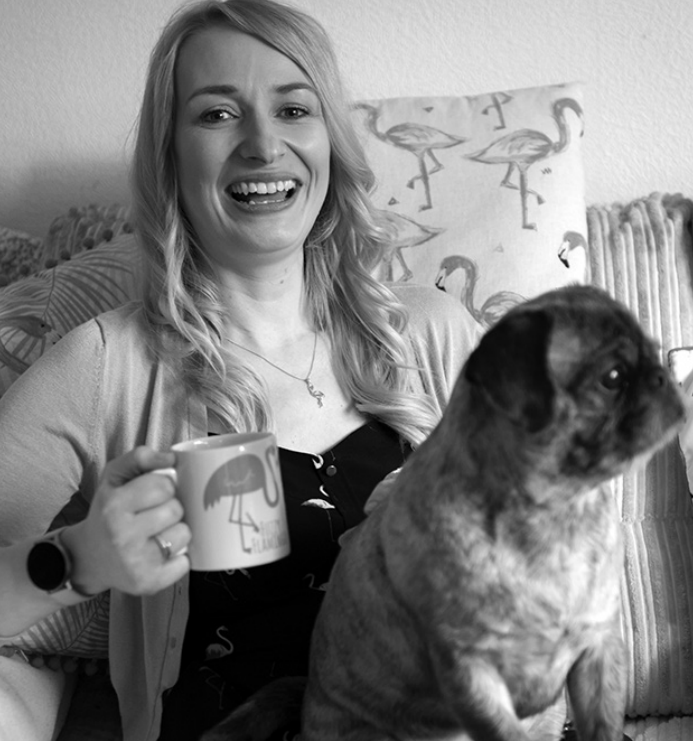 Black and White image of Jen parker holding a cup of tea with her dog on her lap