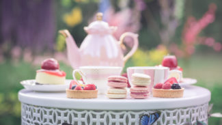 Image of a tea party including a pink teapot and cakes.