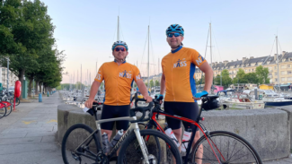 Steve and friend wearing their NASS cycling gear standing in front of their bikes.
