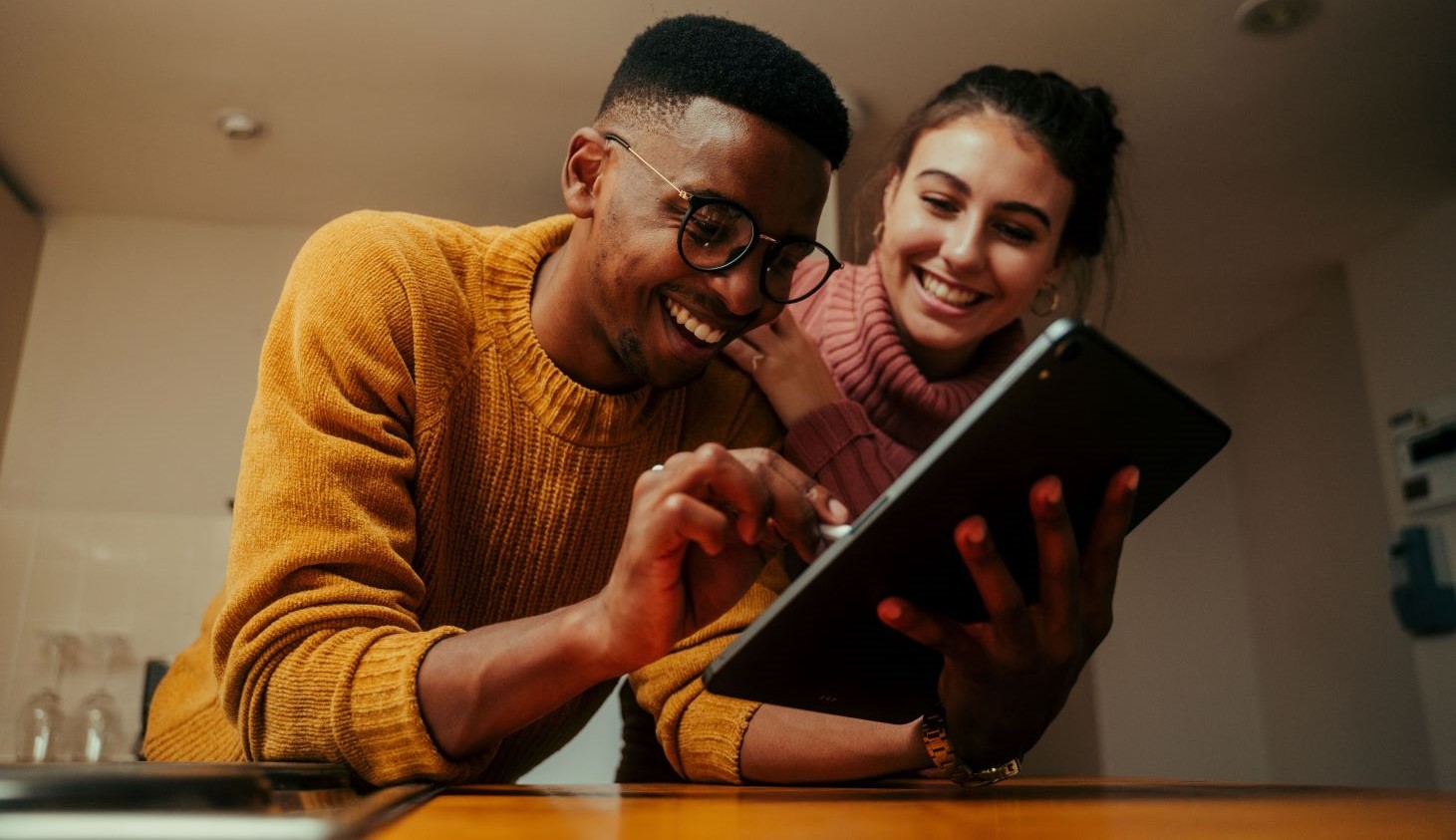 Two people smiling while using an ipad