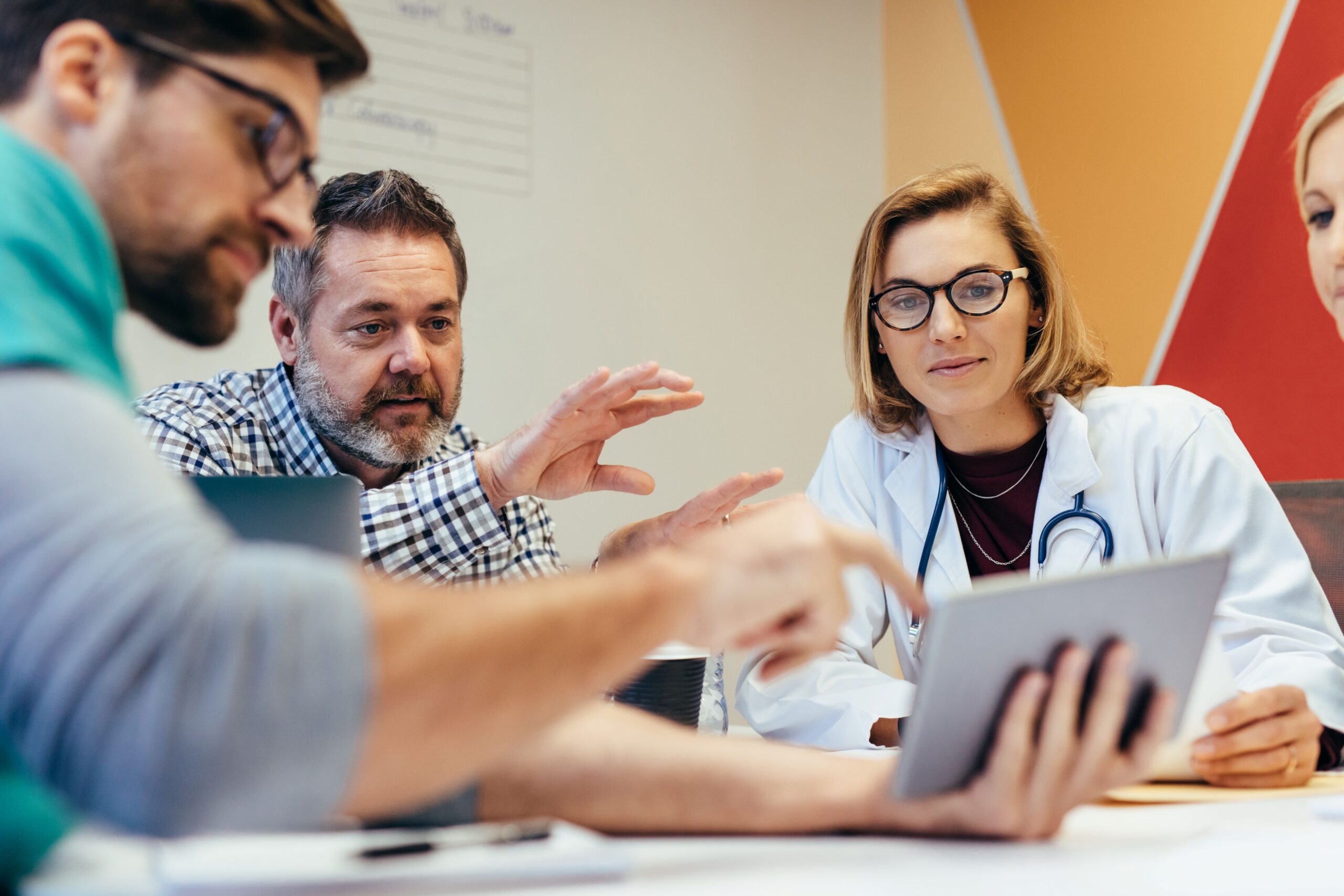 Group of health care professionals sitting around a tablet discussing something